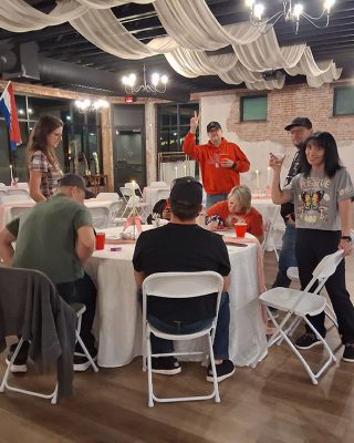 A group of diverse individuals seated around a table engaged in discussion within a well-lit room.