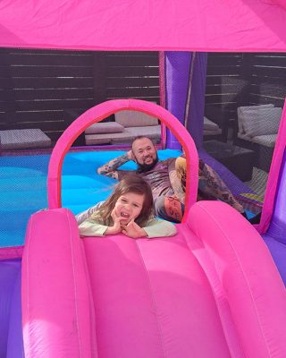 A man and a woman joyfully playing together inside a colorful inflatable bouncer.