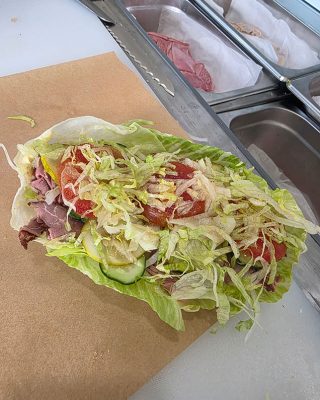 A sandwich placed on a piece of paper, showcasing its layers and ingredients.